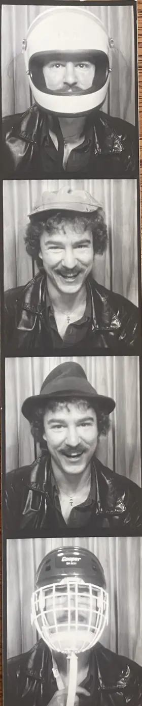A black-and-white photobooth strip: four frames of Robert in a leather jacket, grinning under a motorcycle helmet, a flat cap, a fedora, and a caged hockey helmet.